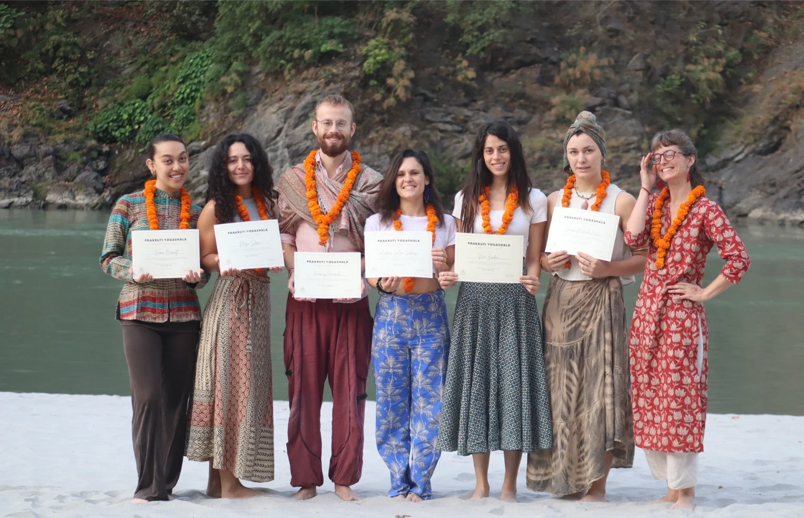Graduating students holding their certificates by the riverside