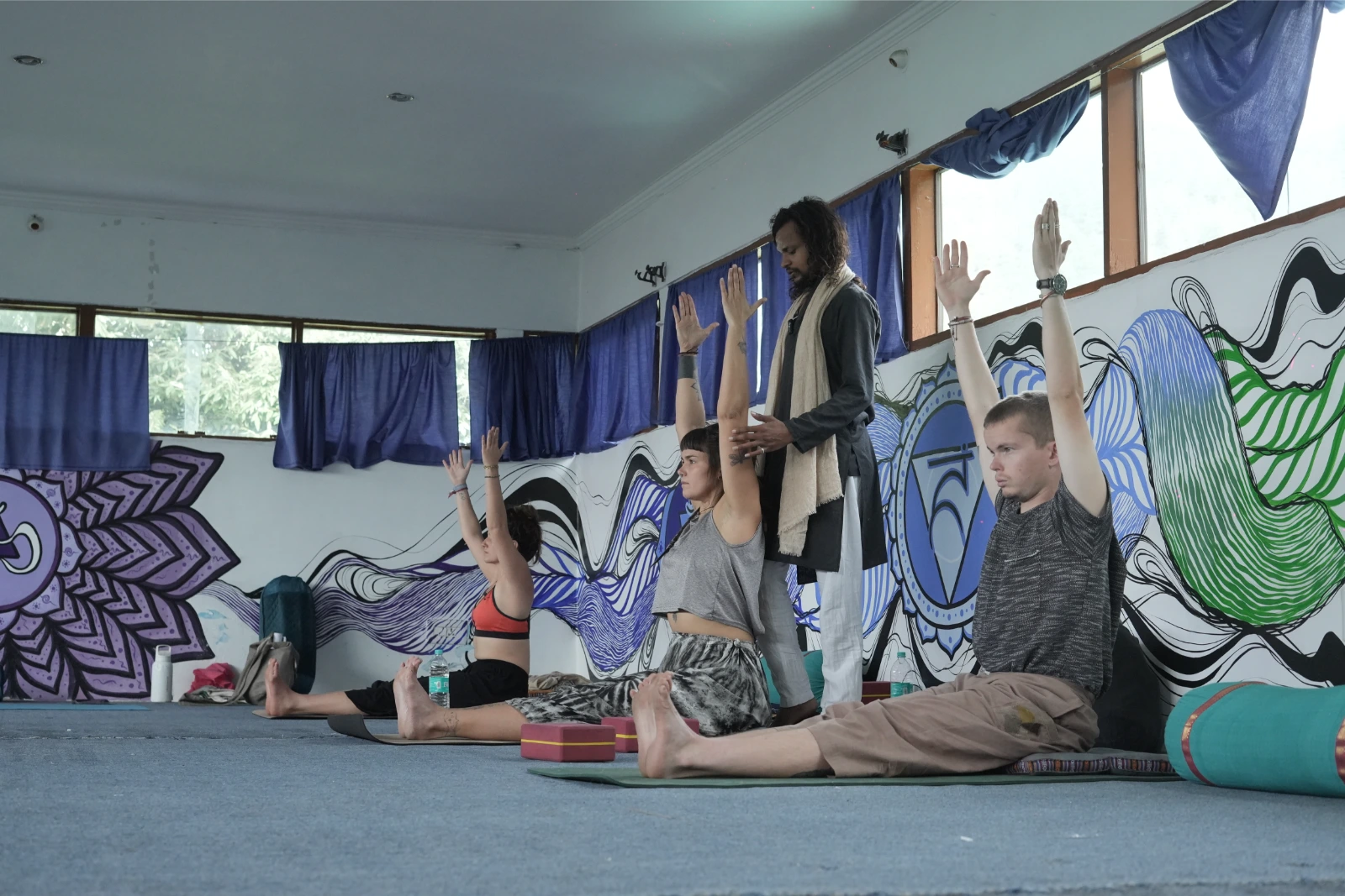 Teacher assisting students during an asana practice session